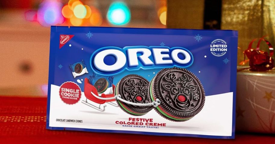 A package of red and green Oreo cookies on a table with holiday lights behind it