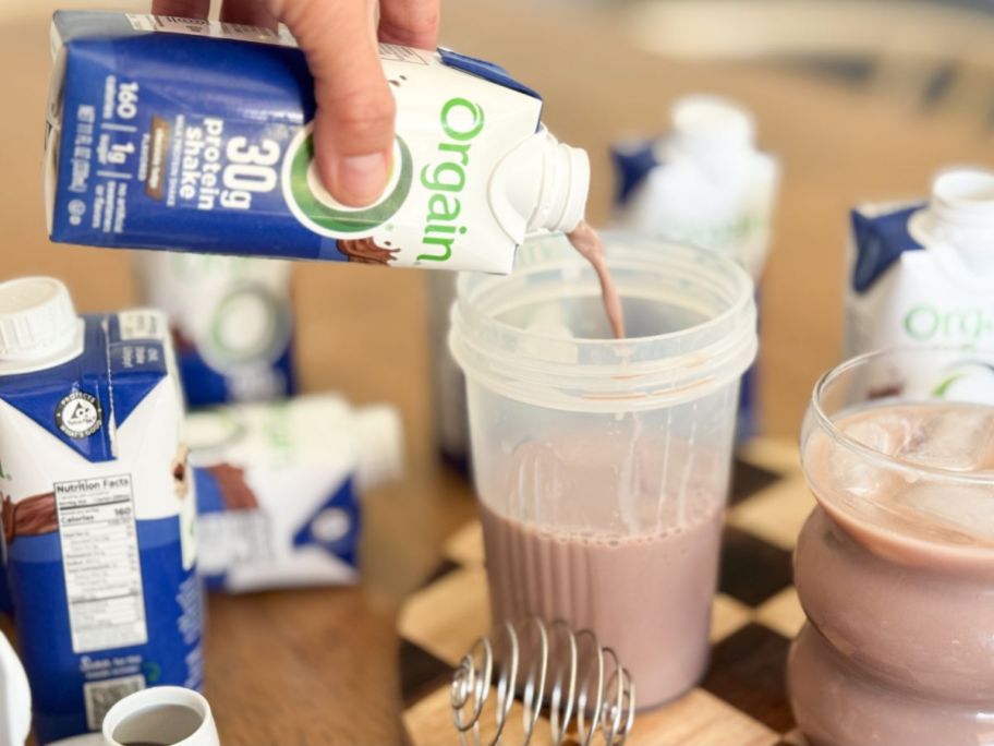 Hand pouring Orgain 30g Protein Shake into a cup