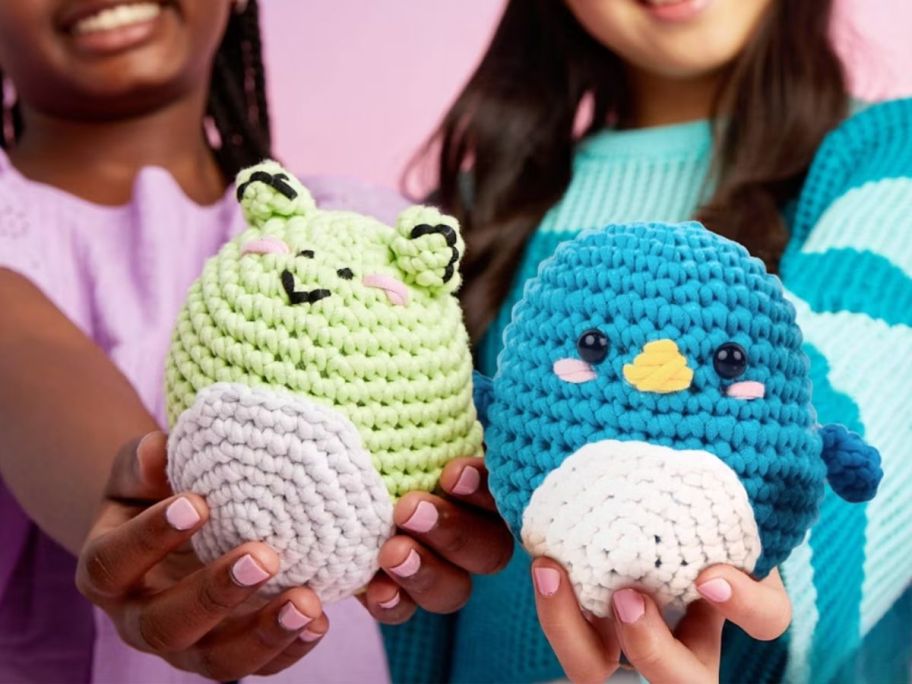 2 kids holding crochet Squishmallow plushies: a frog and a bird