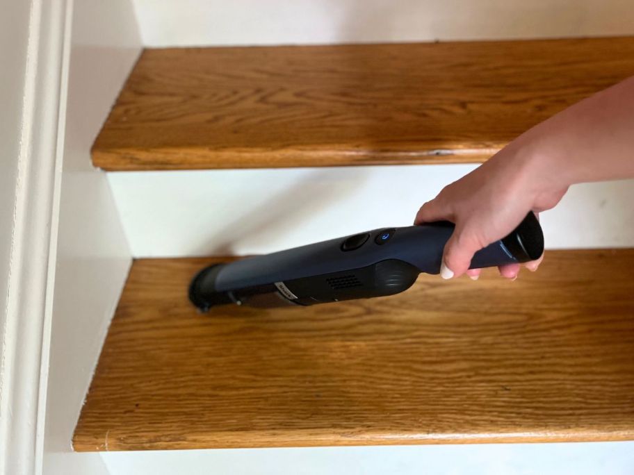 Woman using a Shark Wandvac to clean stairs