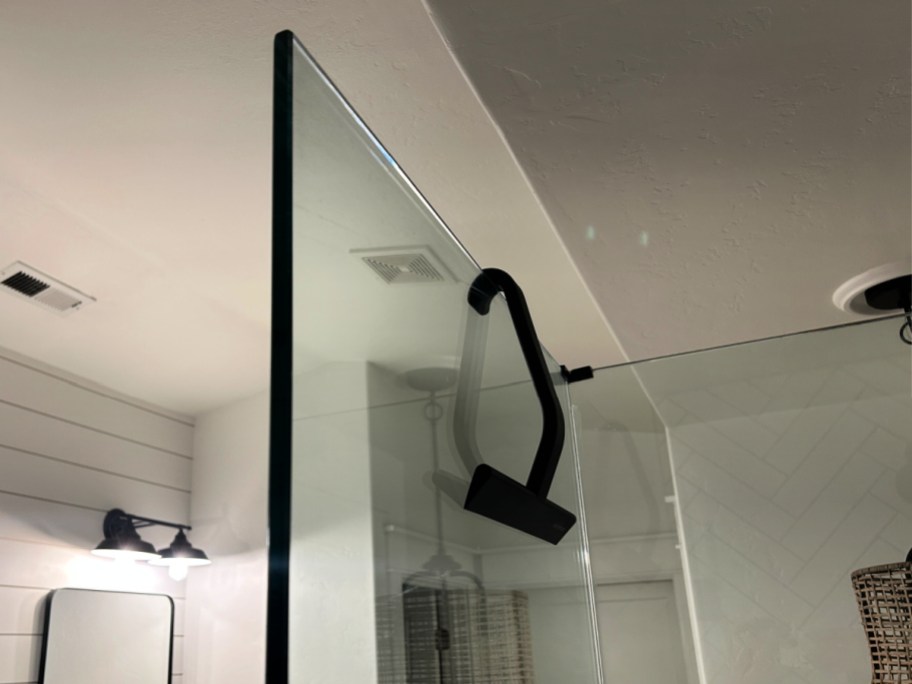 black shower squeegee hanging on glass door