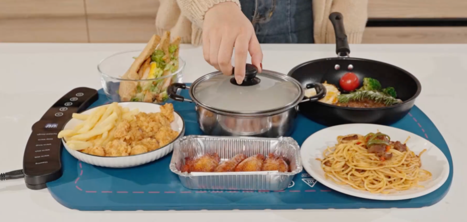 food on plates, foil pans, and cookware sitting on a food warming mat