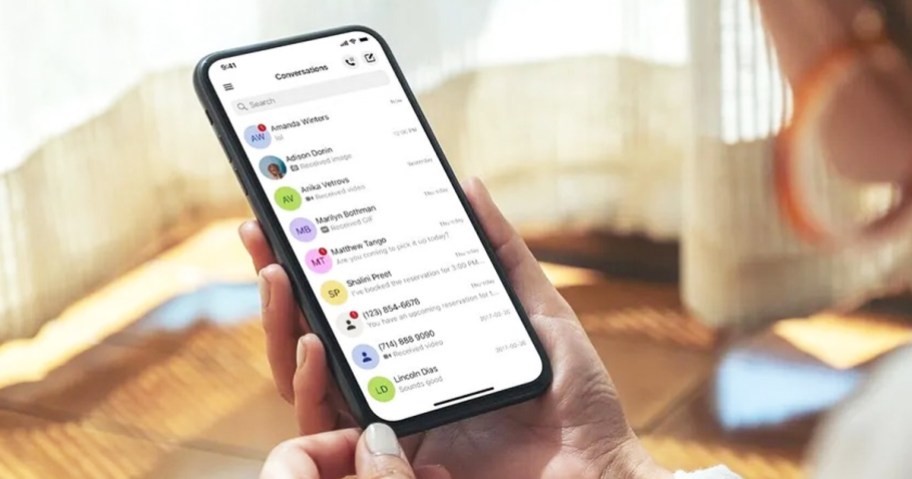 woman holding phone with text conversations open