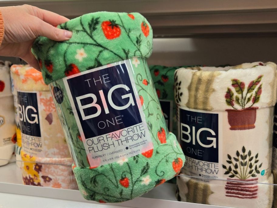 Hand grabbing a strawberry print The Big One Throw Blanket
