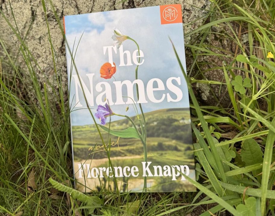 the names book in grass leaning on tree