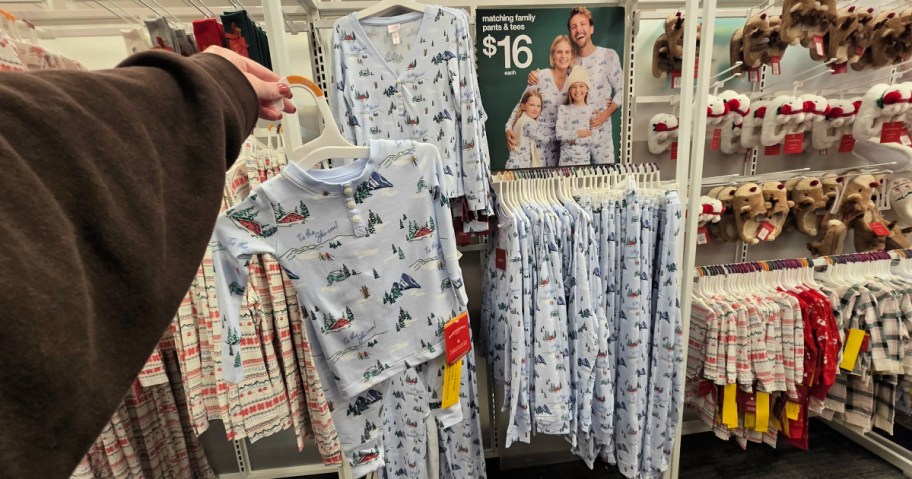 woman holding up a pair of Christmas pajams on a hanger