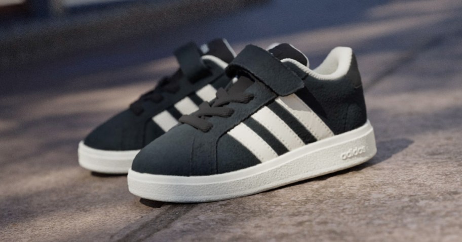 black pair of adidas kids sneakers with 3 white stripes