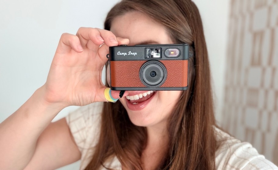 woman holding brown camp snap camera in front of face