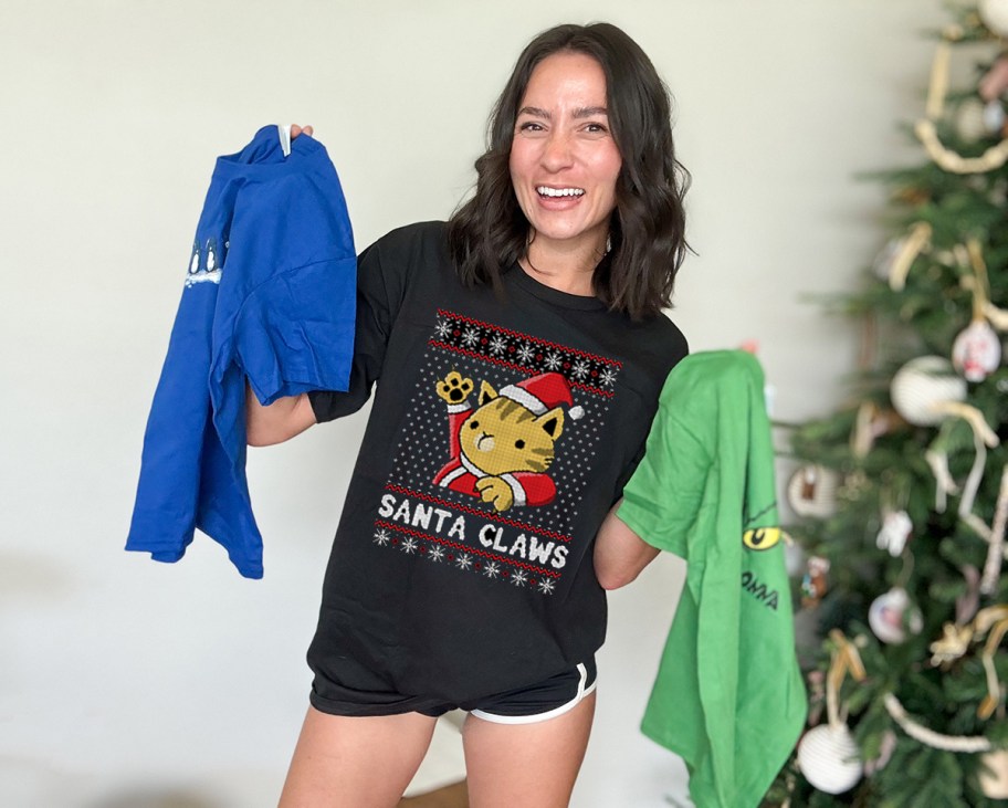 Woman wearing black Santa Claws, holiday T-shirt, and standing in front of Christmas tree