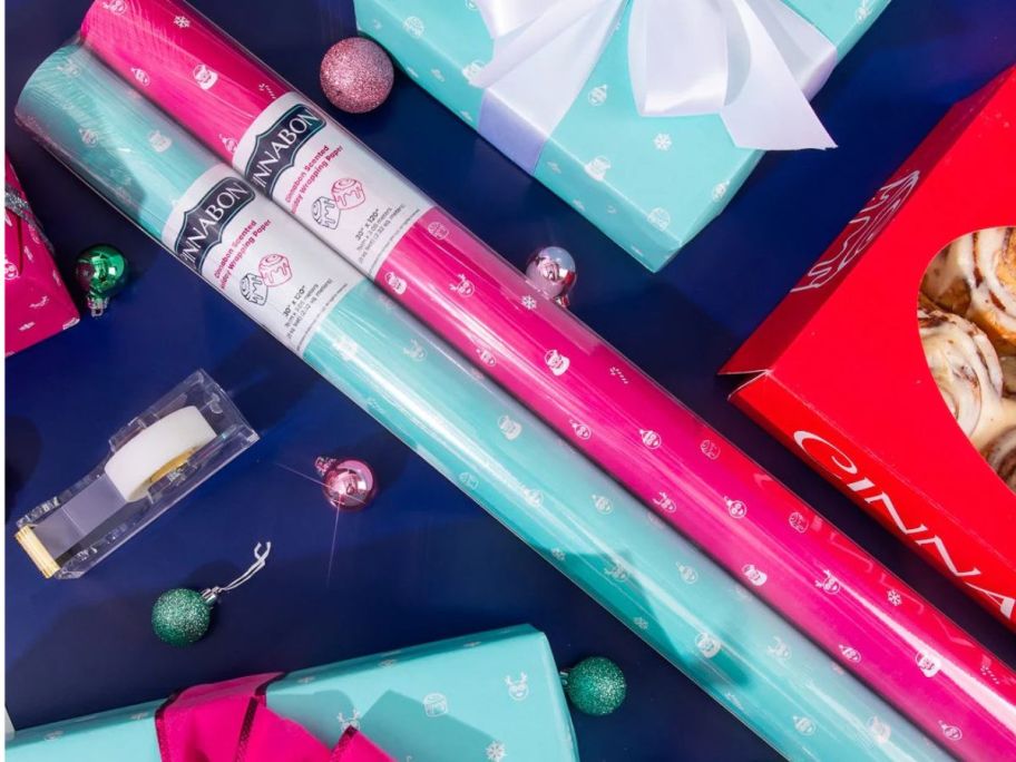 two rolls of Cinnabon wrapping paper on table amongst wrapped gifts