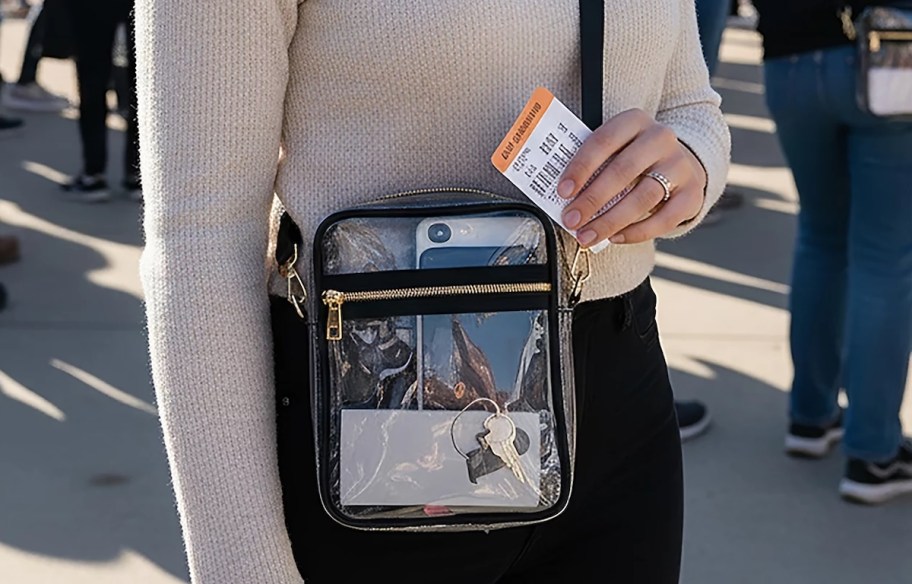 woman wearing clear crossbody holding ticket