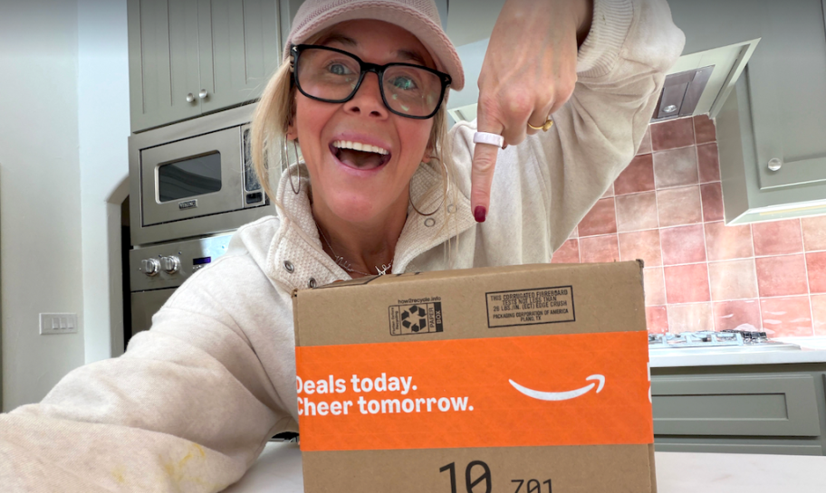 woman holding amazon box smiling in kitchen