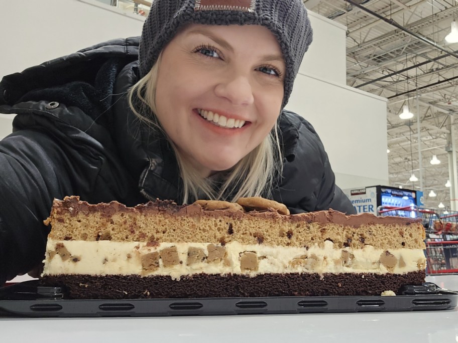 A woman holding up the chocolate chip cookie bar cake from Costco.