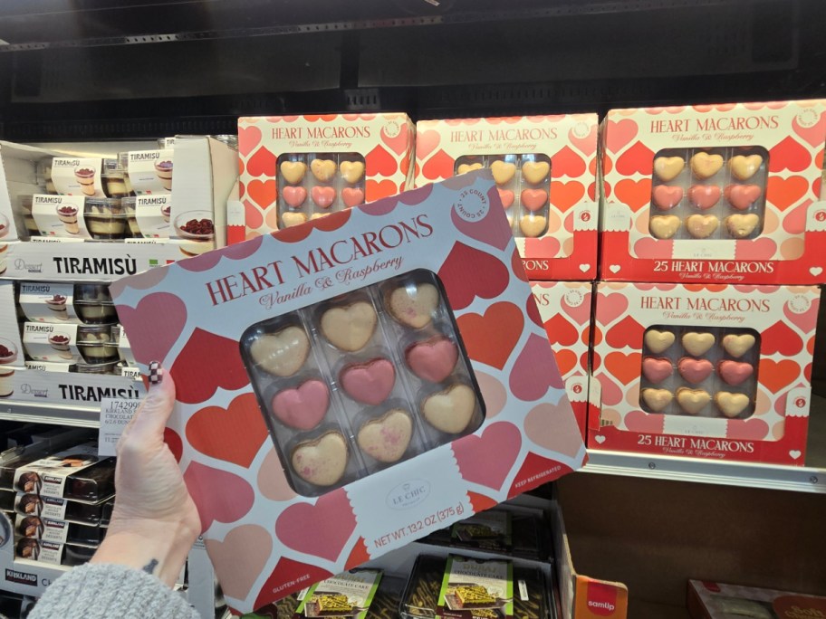A hand holding up a box of Heart Macarons at Costco.