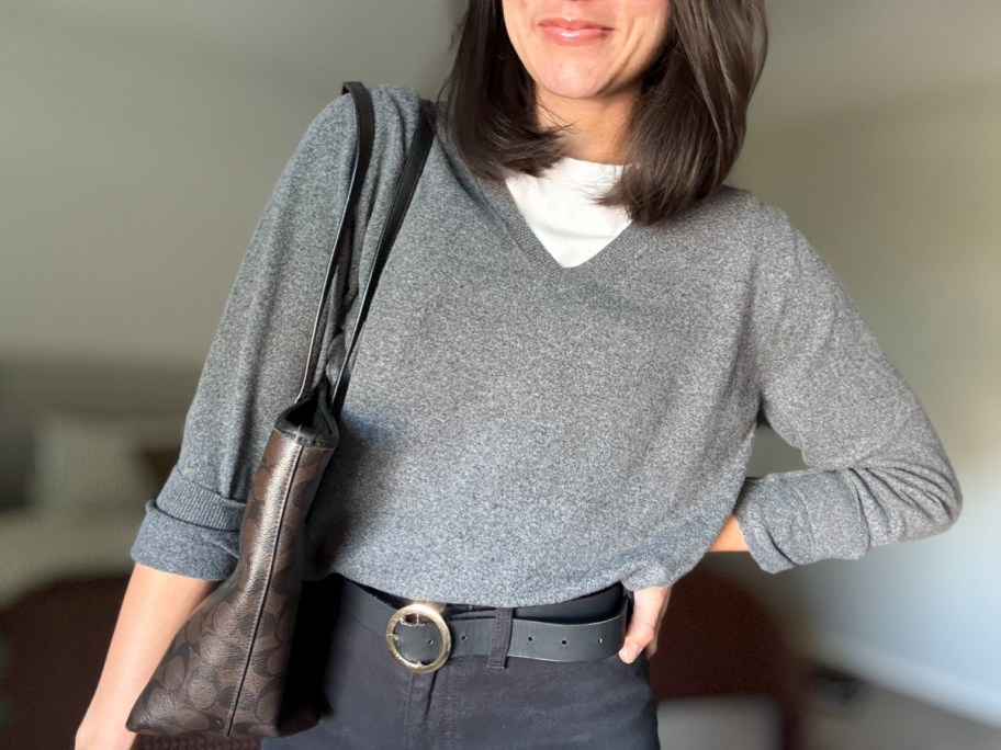 smiling woman wearing a sweater with a purse over her shoulder
