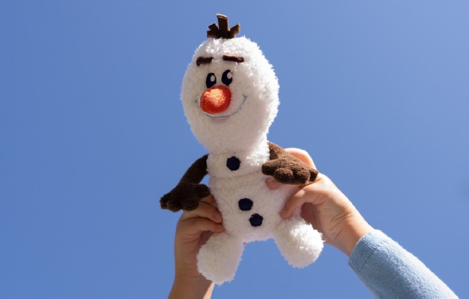 child holding up an olaf disney plush