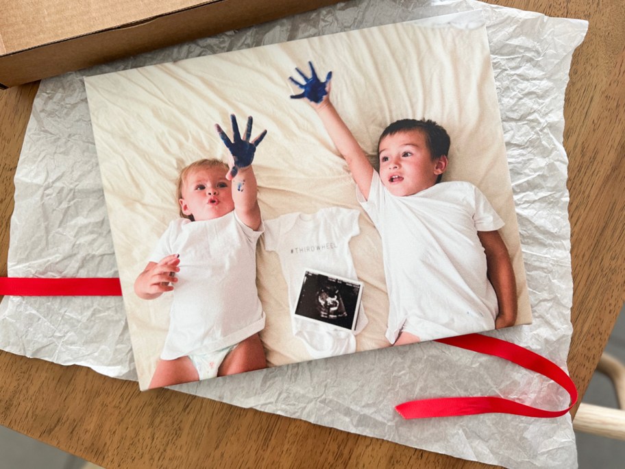 canvas print with two kids on it on table with red ribbon 