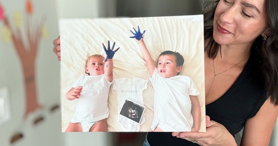 woman holding canvas print with two kids on it 