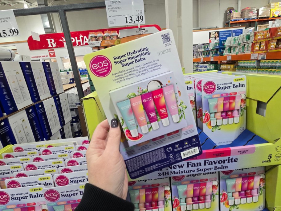 A hand holding up a pack of eos lip balms.