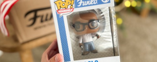hand holding funko pop figure in box next to cardboard box