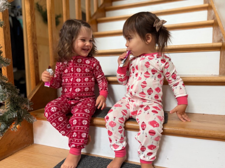 two young girls wearing christmas PJs and sitting on a staircase