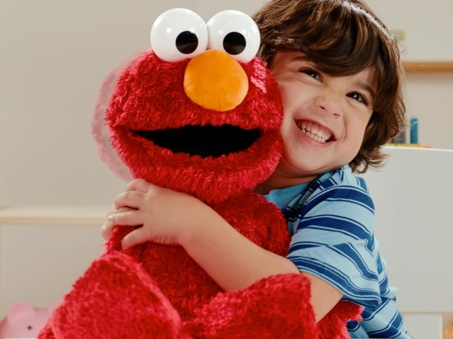 boy holding a plush elmo
