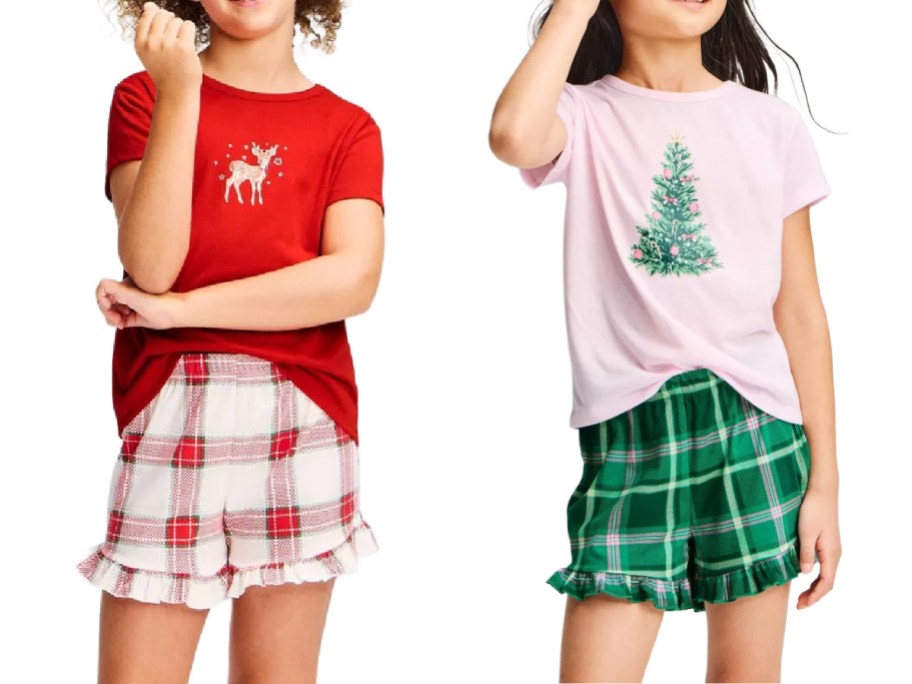 Cat & Jack girls' holiday pajama sets including a red short-sleeve shirt with a reindeer graphic paired with white and red plaid ruffle shorts, and a light pink shirt featuring a decorated Christmas tree paired with green plaid ruffle shorts.