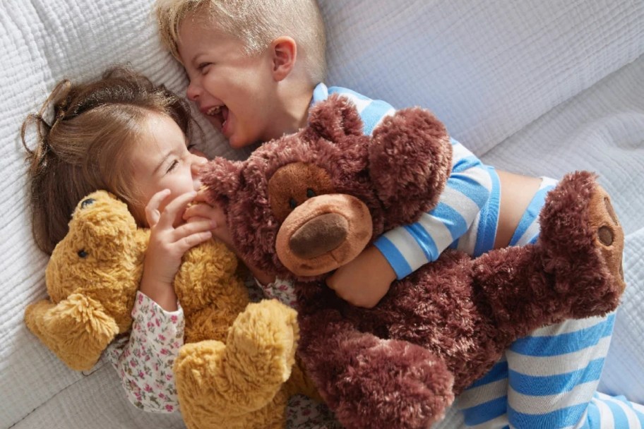 two kids laughing and snuggling stuffed plush