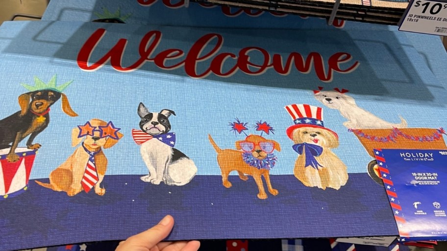 a womans hand grabbing a doormat off a store shelf in a lowes store