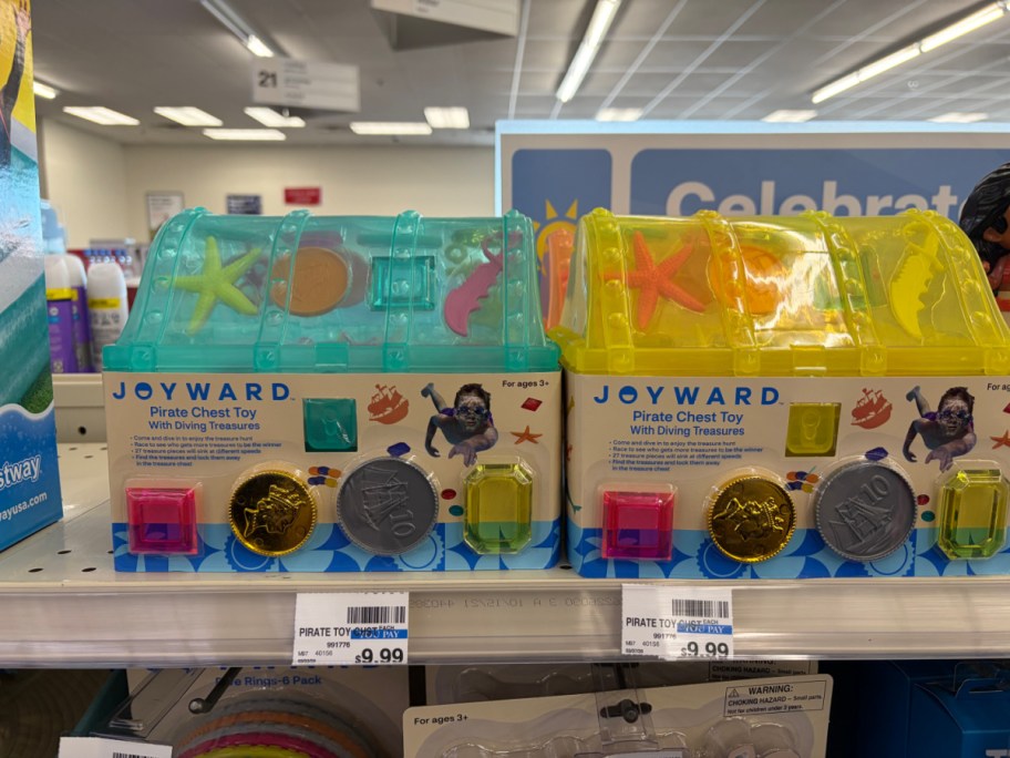Two packaged Joyward Pirate Chest Toys side-by-side on a store shelf: a teal chest on the left and a yellow chest on the right.