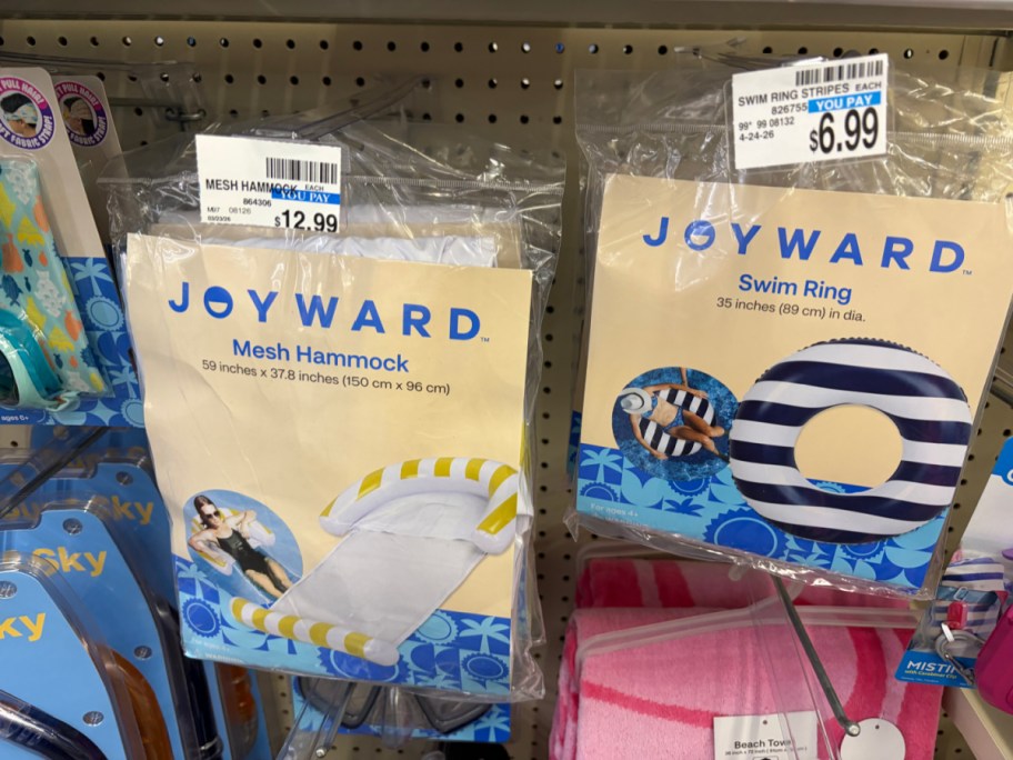 Two packaged Joyward pool floats hanging side-by-side on a store pegboard: a mesh hammock on the left, and a navy and white striped swim ring on the right.