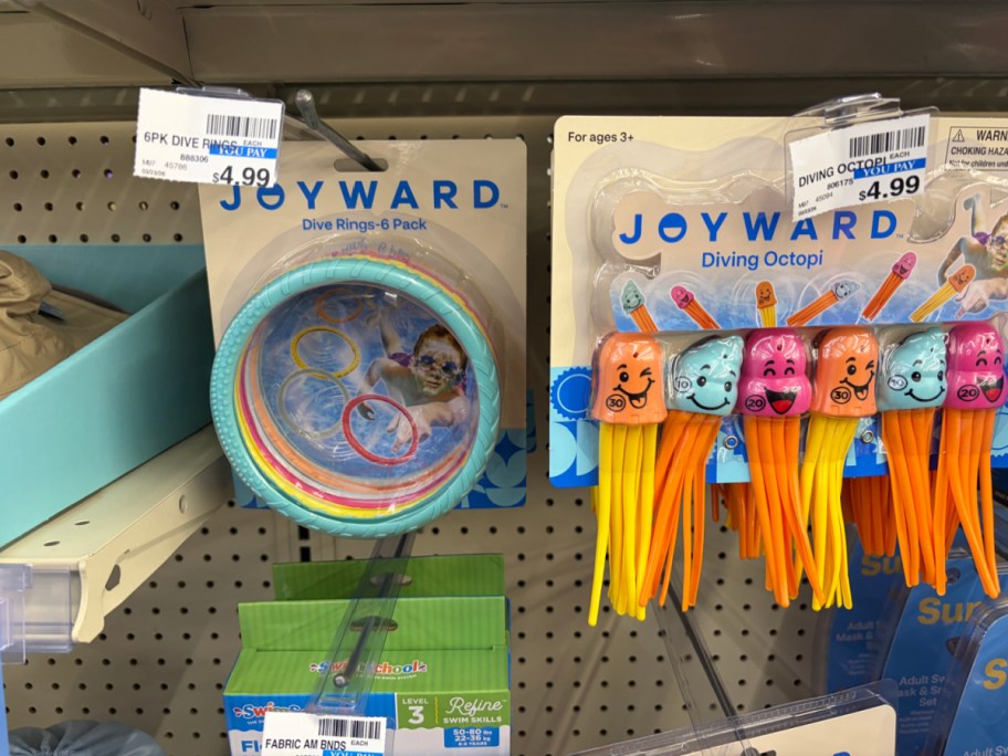 Two packaged Joyward pool toys hanging side-by-side on a store pegboard: a 6-pack of dive rings on the left, and a set of colorful diving octopi on the right.