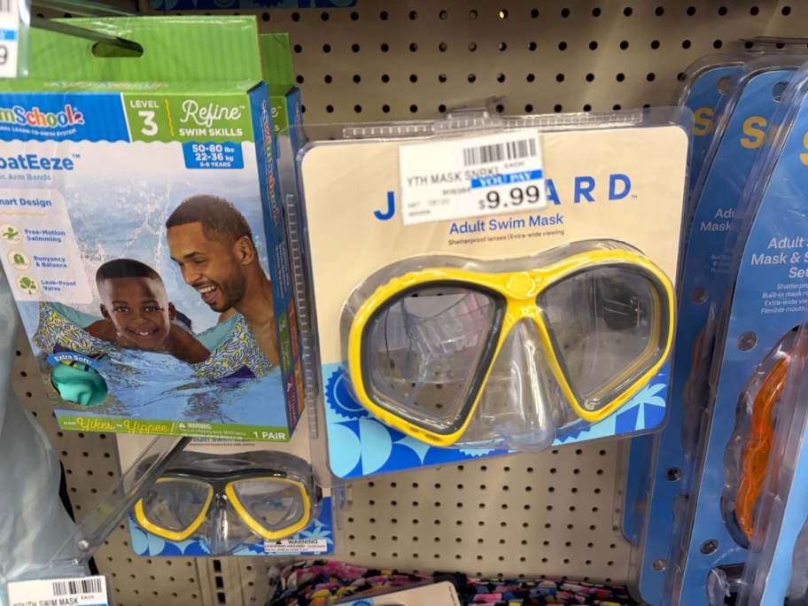 A packaged yellow and black Joyward adult swim mask hanging on a pegboard in a store aisle.