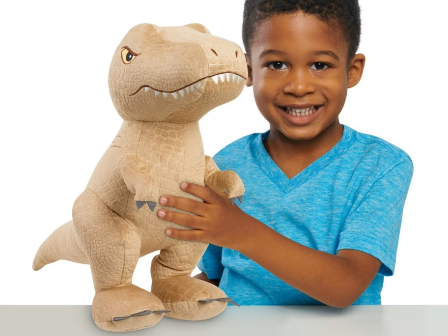 young boy playing with a plush jurassic world dinosaur toy