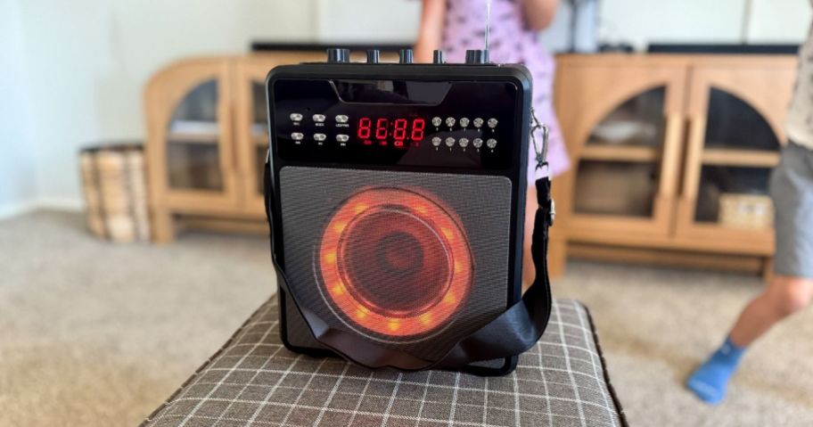 karaoke machine on ottoman with kids singing behind it