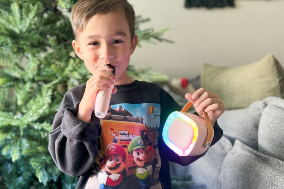 kid using pink microphone and holding mini karaoke machine