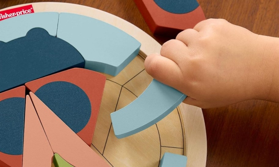 a toddlers hand assembling a lady bug puzzle 