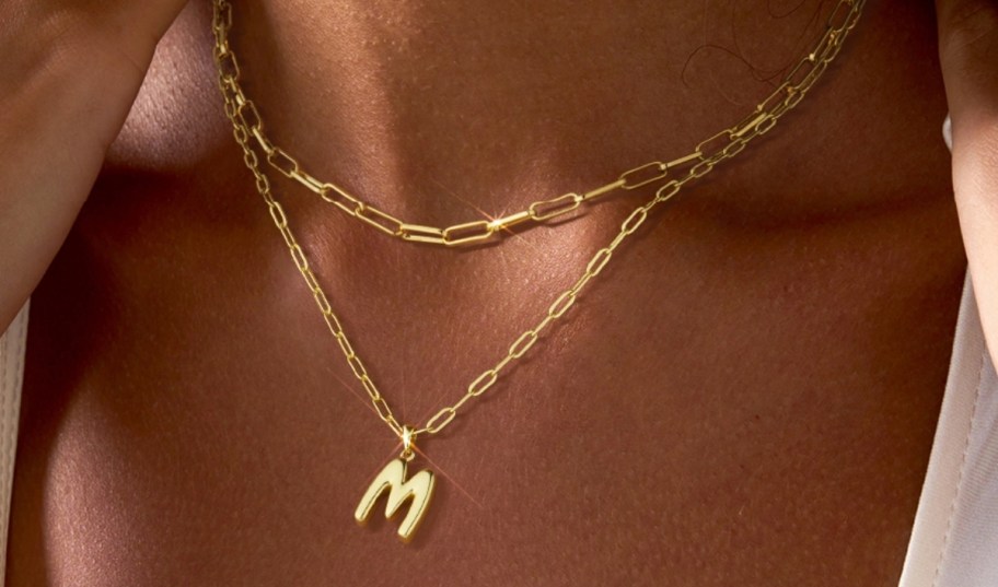a woman wearing a layered initial necklace
