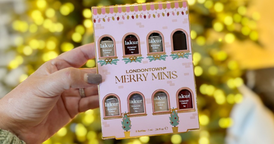 hand holding londontown merry minis in front of christmas tree