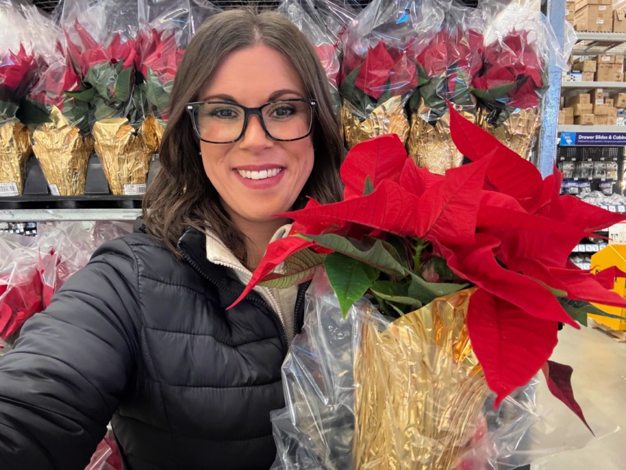 smiling woman holding a poinsettia in a store