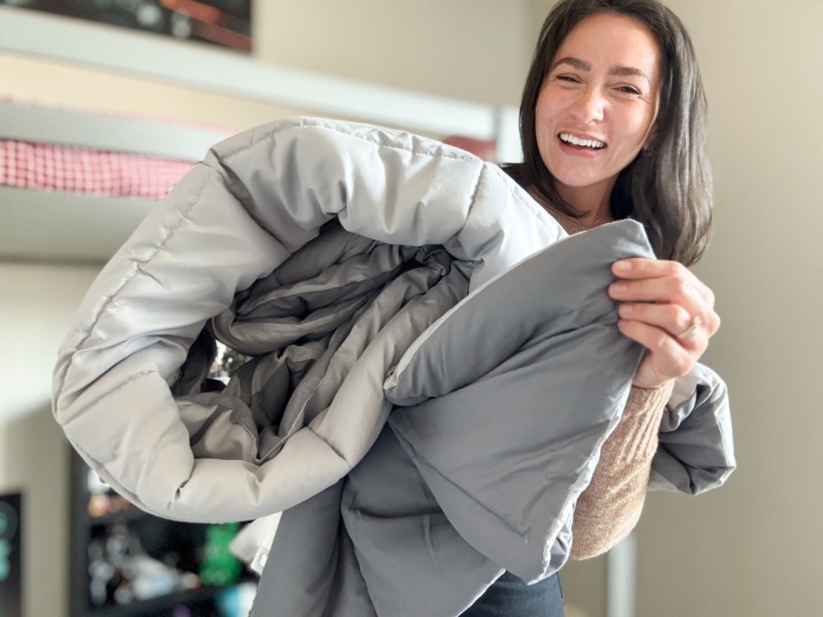 woman holding grey double sided comforter