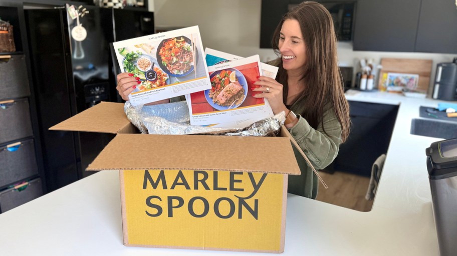 woman holding pamphlets of marley spoon recipes from delivery box