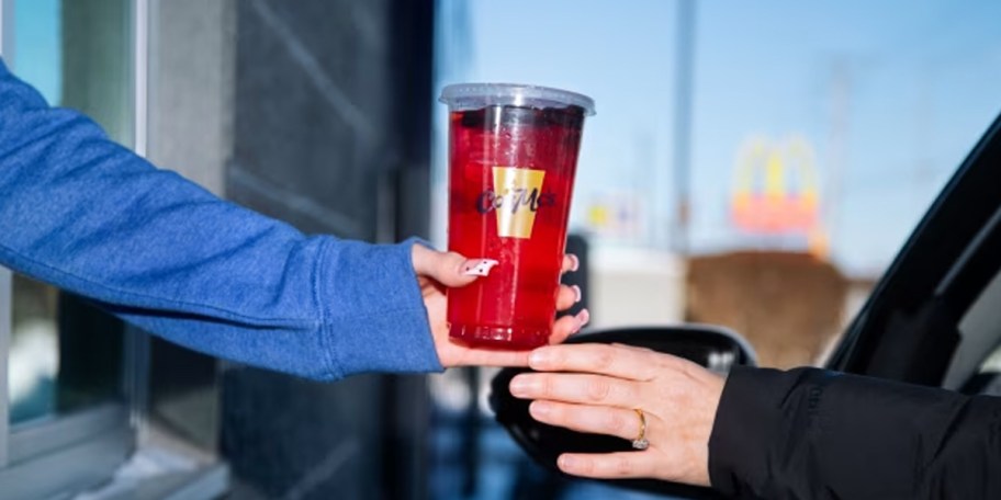 hand giving drink to someone in car 
