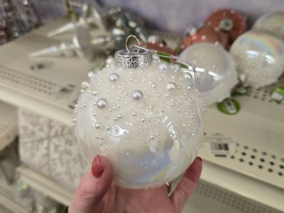Iridescent White Glass Ball Ornament in hand in store