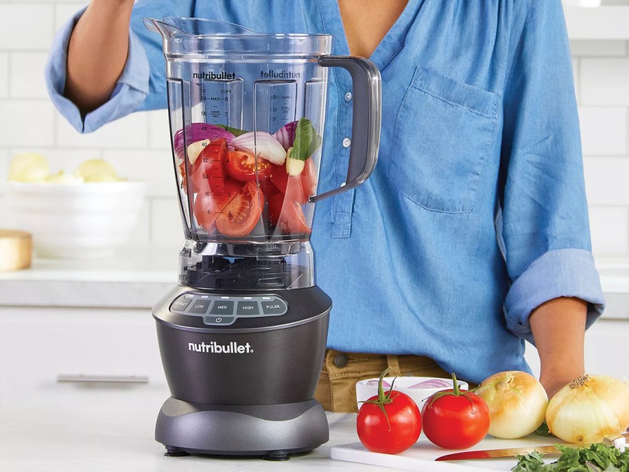 Person packing fruits and vegetables into blender