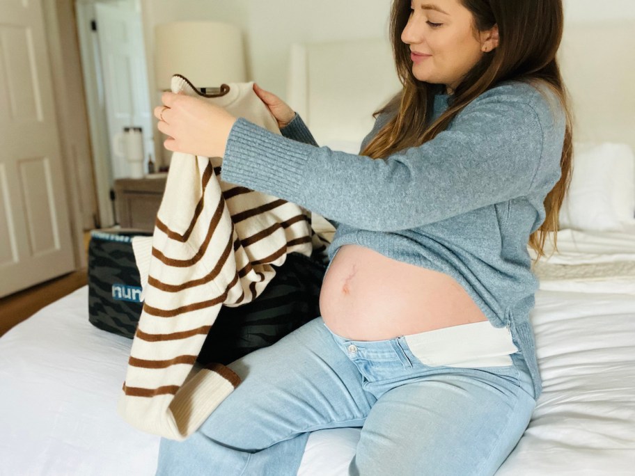 woman holding up stripe sweater from nuuly delivery bag