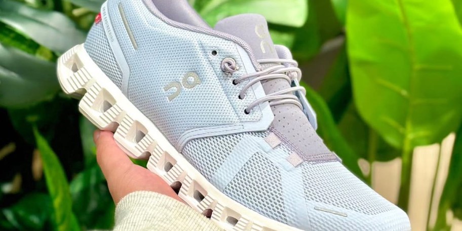 hand holding blue and white on cloud running shoe