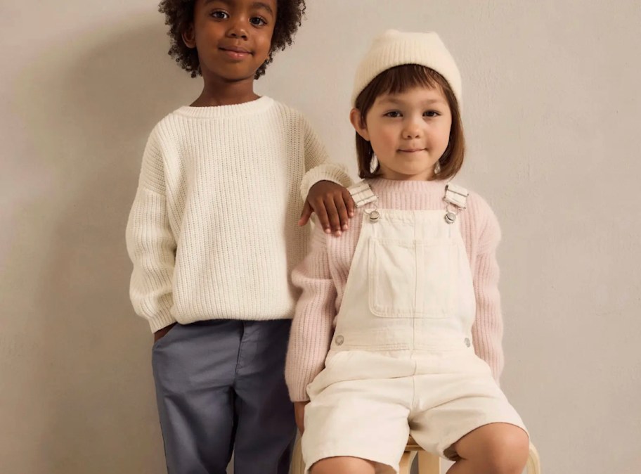 two kids modeling winter cashmere sweaters in white and pink