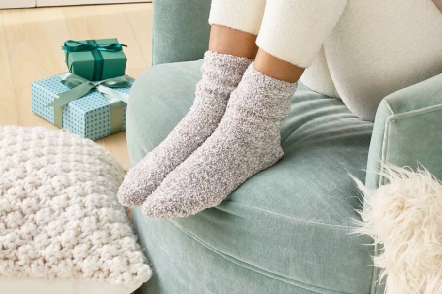 woman in grey socks putting feet up on green couch