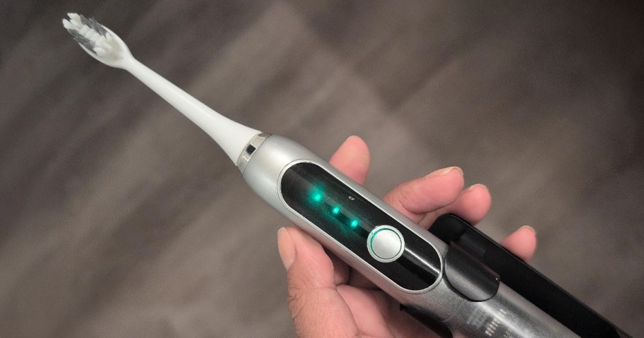 person holding a silver electric toothbrush
